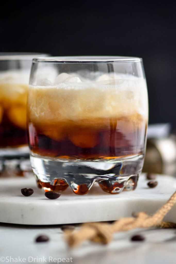 Glass of white russian cocktail with ice and coffee beans