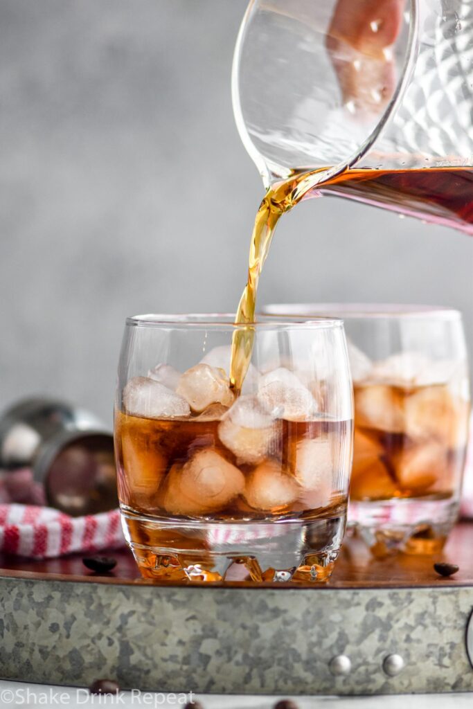 Making white russian cocktail recipe in a glass with ice