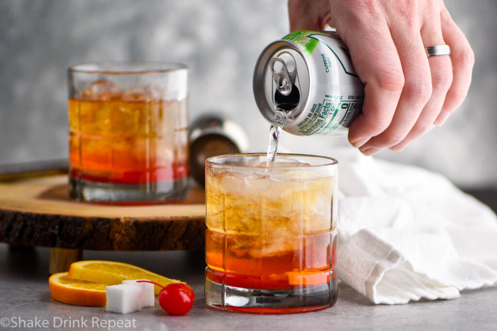 two glasses of wisconsin Old Fashioned with ice, sugar cube, cherry, orange, and lemon-lime soda