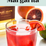 glass of blood orange margarita with ice and blood orange wedge garnish