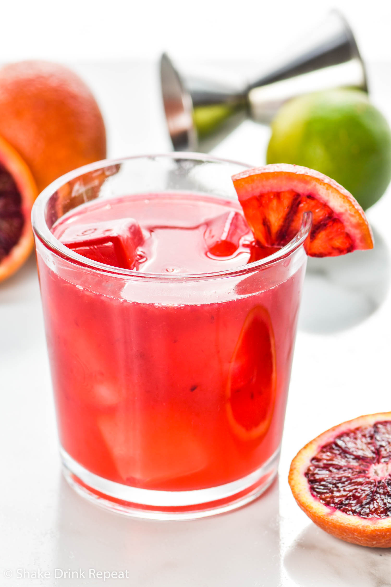 glass of blood orange margarita with ice and blood orange wedge garnish