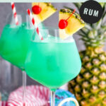 two glasses of blue hawaii with ice, straws, pineapple, and cherry