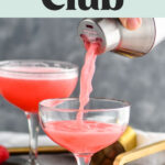 man pouring shaker of clover club cocktail into a glass with raspberries