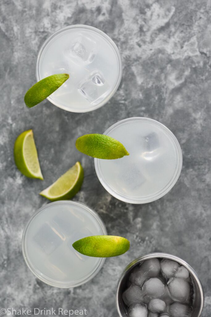 three glasses of gin gimlet with ice and lime wedges