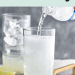 man pouring club soda water into a glass of gin rickey and ice surrounded by lime wedges