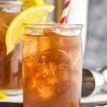 two glasses of long island iced tea with ice, a straw and lemon garnish