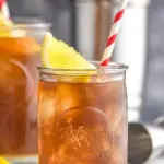 glass of long island iced tea with ice, straw and lemon