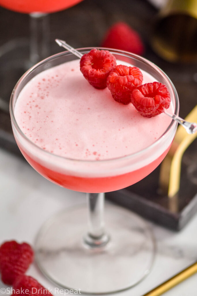 glass of clover club cocktail with raspberry garnish