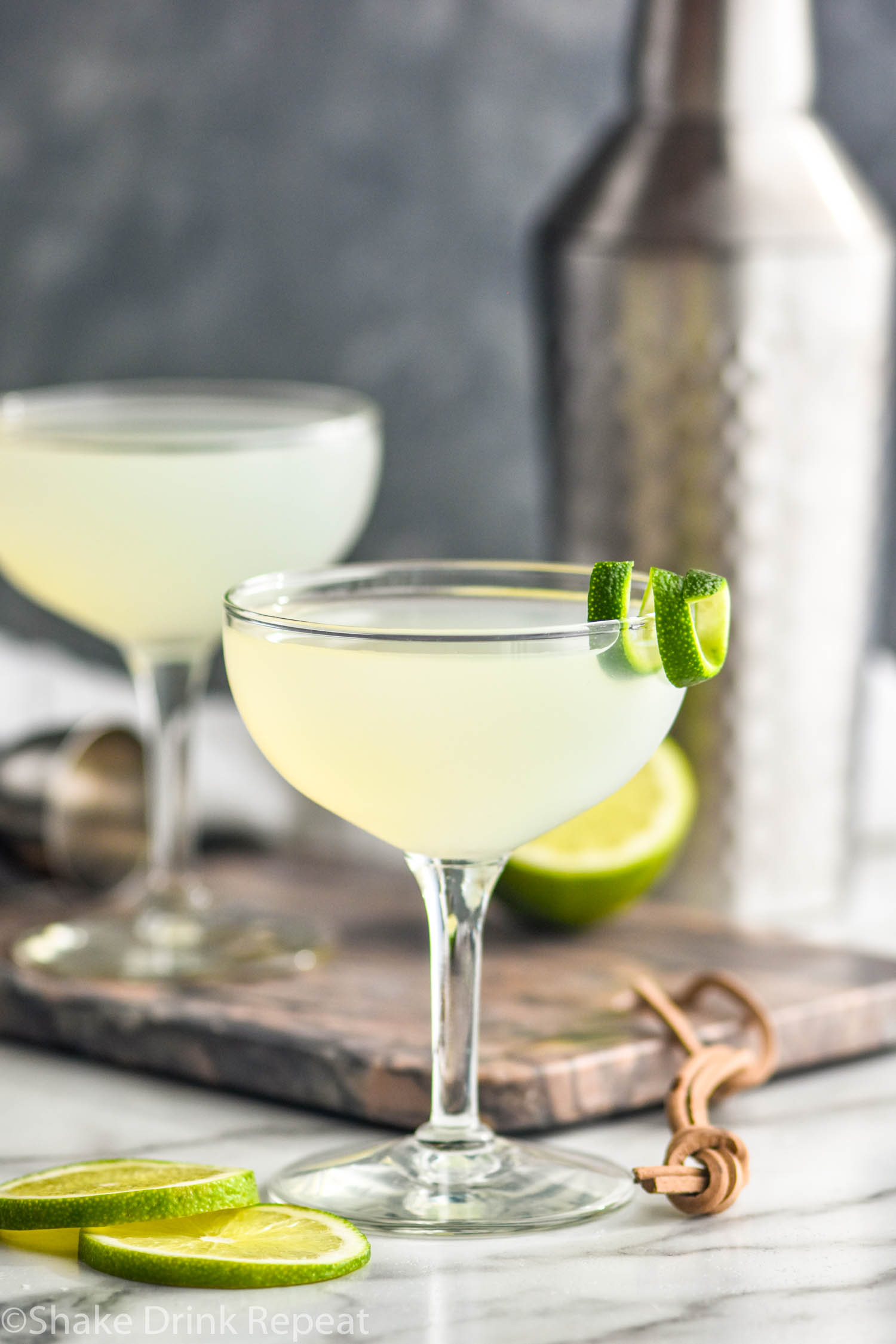 two cocktail glasses of daiquiri with lime twist