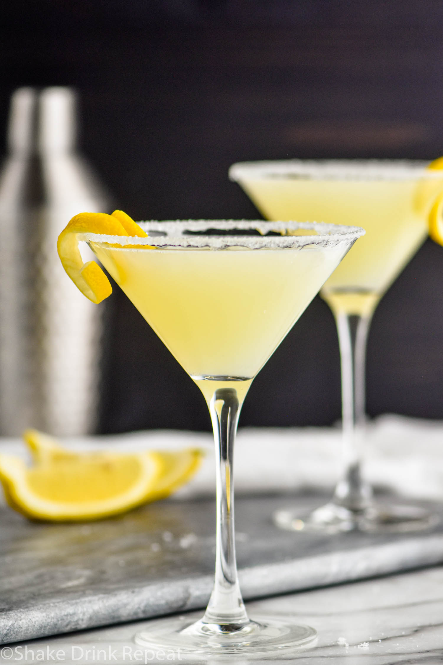 two glasses of lemon drop martini with sugared rims and a lemon twist