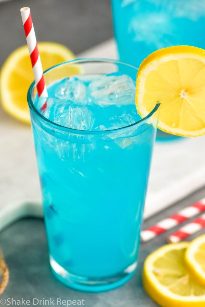 glass of walk me down cocktail with ice, a straw, and lemon slices