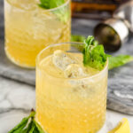 two glasses of whiskey smash with ice, mint and lemon