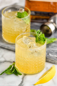 two glasses of whiskey smash with ice, mint and lemon