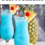 two glasses of blue hawaiian with ice, straws, pineapple, and cherries