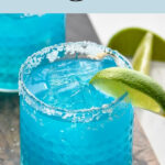 Glass of Blue Margarita with ice, salted rim, and fresh lime wedge