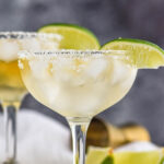 two glasses Cadillac Margarita with ice, salted rim, and lime wedge garnish