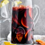 pitcher of red sangria with slices of fresh fruit, lemons, and oranges