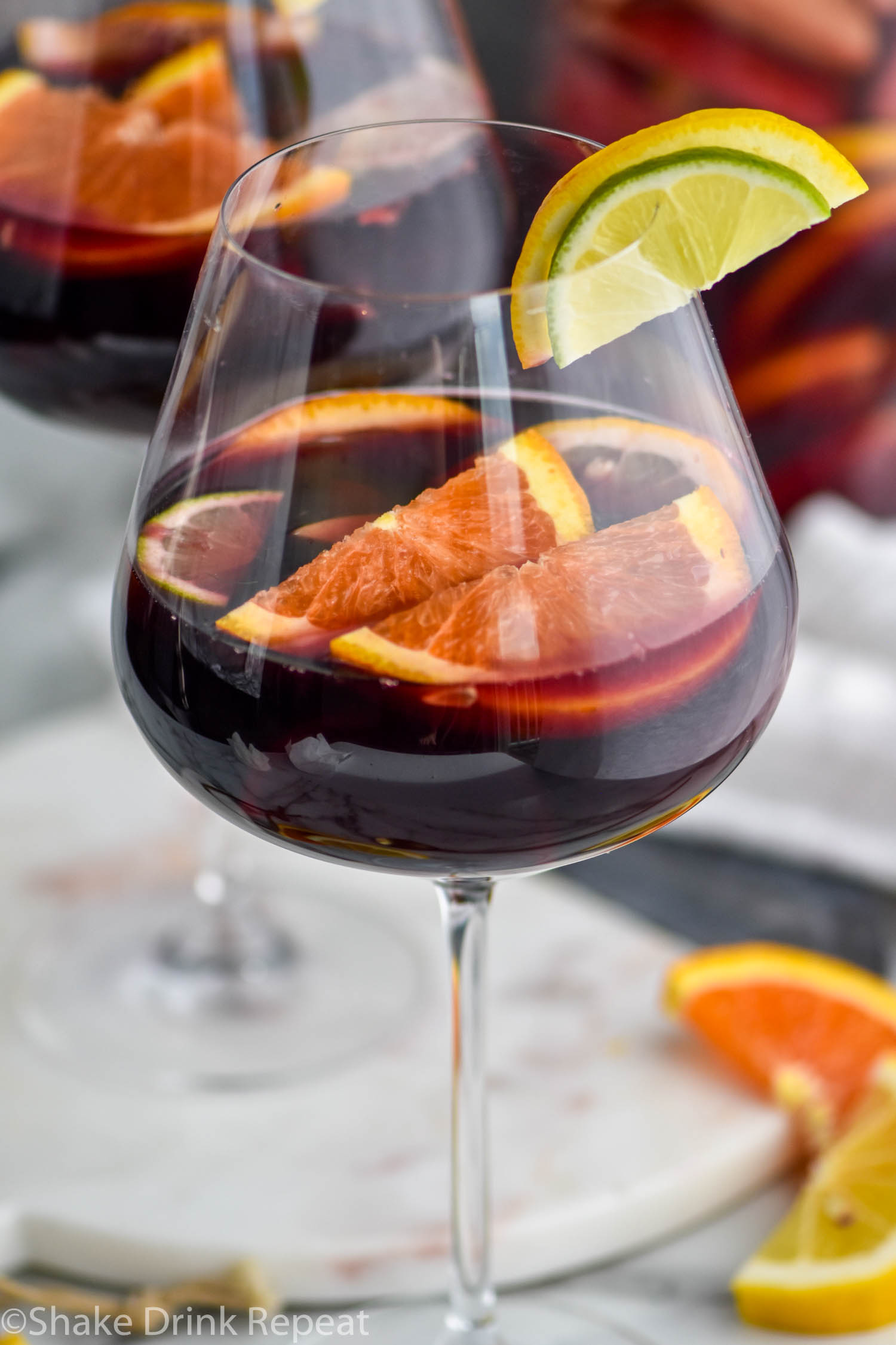 glass of red sangria with slices of fresh fruit including lemons, limes, and oranges