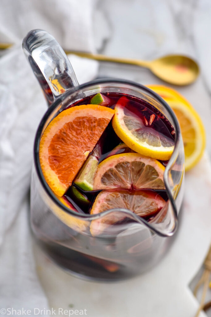 pitcher of red sangria with slices of fresh fruit including lemons, limes, ad oranges