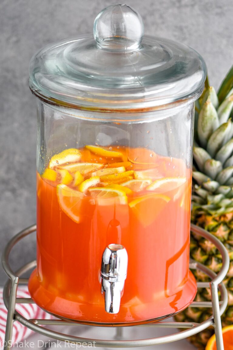 Glass dispenser of rum punch and fresh orange slices