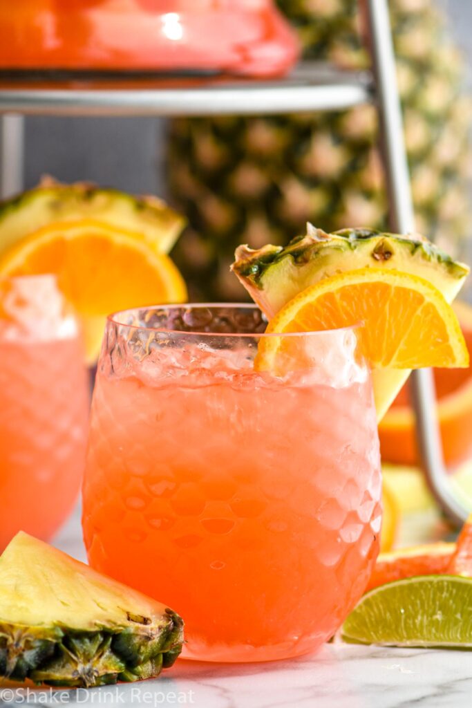 glass of rum punch with ice, slices of pineapple, orange, and lime