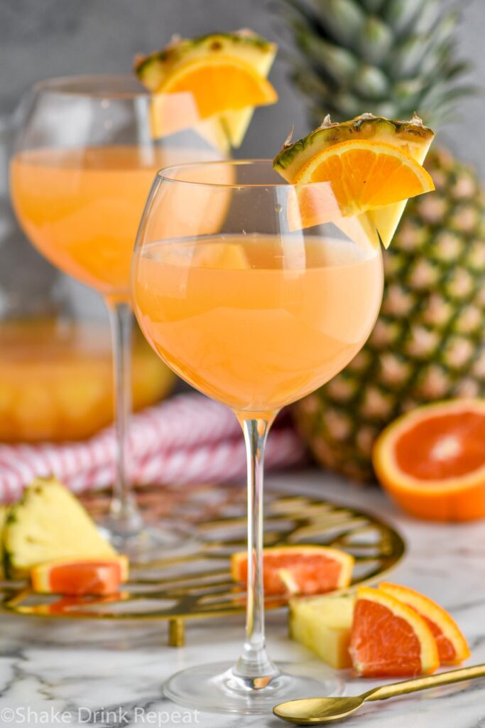 two glasses of tropical sangria with slices of fresh pineapple and oranges