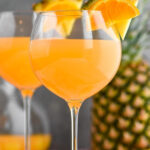 pitcher and glasses of tropical sangria with slices of fresh pineapple and oranges