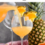 pitcher and glasses of tropical sangria with slices of fresh pineapple and oranges