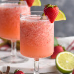 two glasses of virgin strawberry daiquiri with fresh strawberries and lime garnish