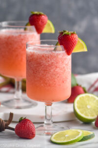 two glasses of virgin strawberry daiquiri with fresh strawberries and lime garnish