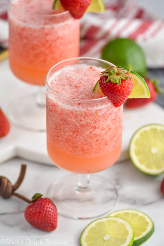 two glasses of virgin strawberry daiquiri with fresh strawberries and lime garnish