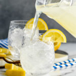 man pouring pitcher of lemonade into a glass of vodka and ice with lemon garnish