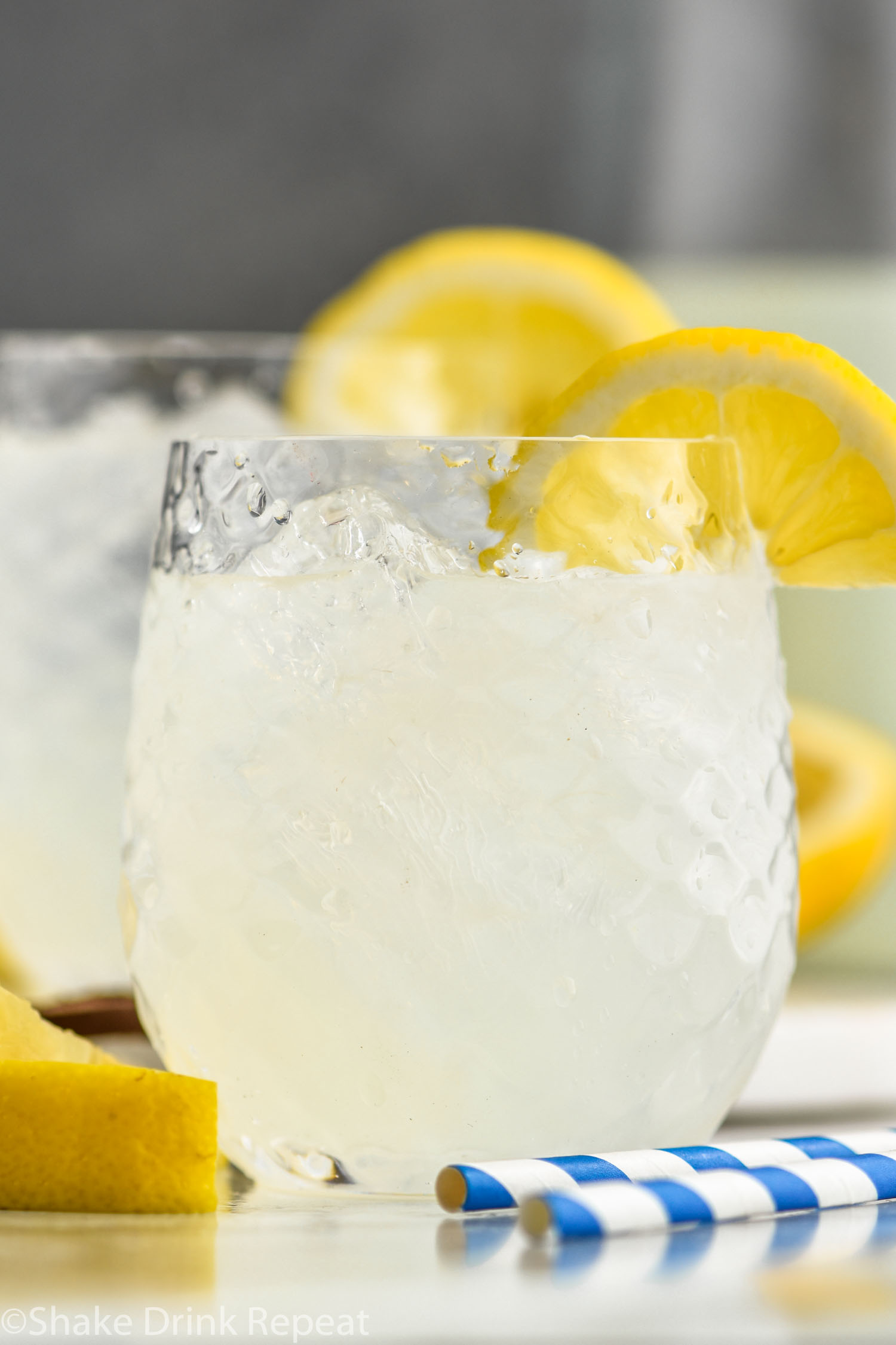 two glasses of vodka lemonade with ice, straws, and lemon slices