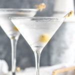 two chilled martini glasses of vodka martini with olive garnish