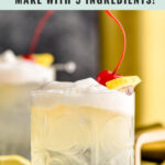 glass of vodka sour with frothy egg white and slice of lemon and cherry garnish with spoon in front