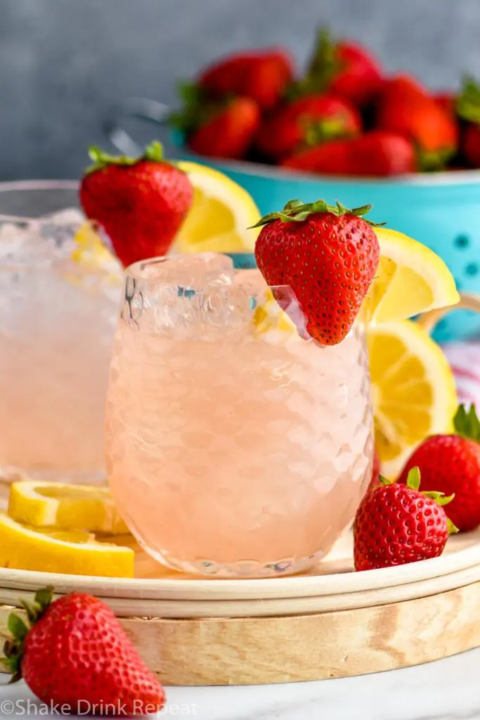 two glasses of vodka strawberry lemonade with ice, strawberries and lemon slices