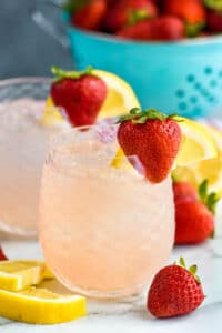 two glasses of vodka strawberry lemonade with ice, fresh strawberries, and lemon slices