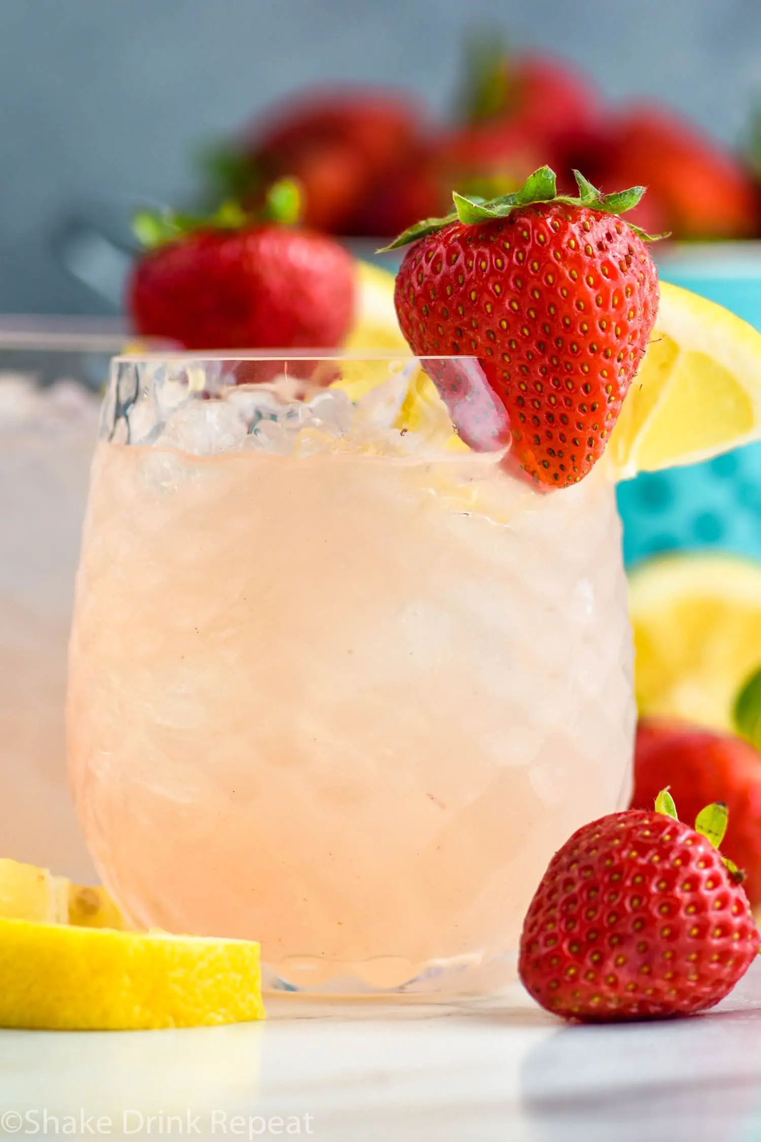 glass of vodka strawberry lemonade with ice, fresh strawberries, and lemon slices