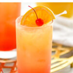 glass of tequila sunrise with ice, orange slice and cherry garnish