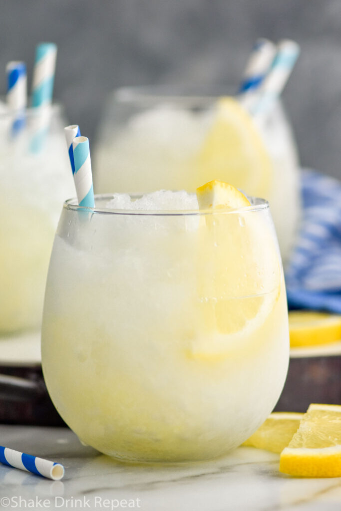 three glasses of frozen lemonade with straws and garnished with slices of lemon