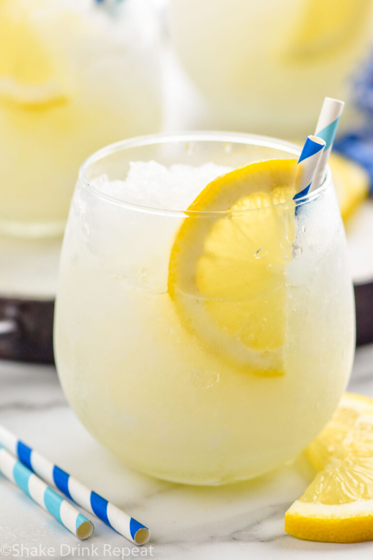 glass of frozen lemonade with a straw and lemon slice garnish