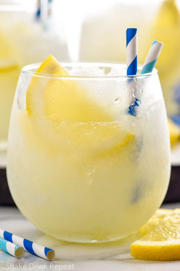 glass of frozen lemonade with straws and slice of lemon garnish