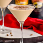 two martini glasses of Mudslide recipe surrounded by chocolate shavings, two straws, a bottle of Bailey's and a bottle of Kahlua