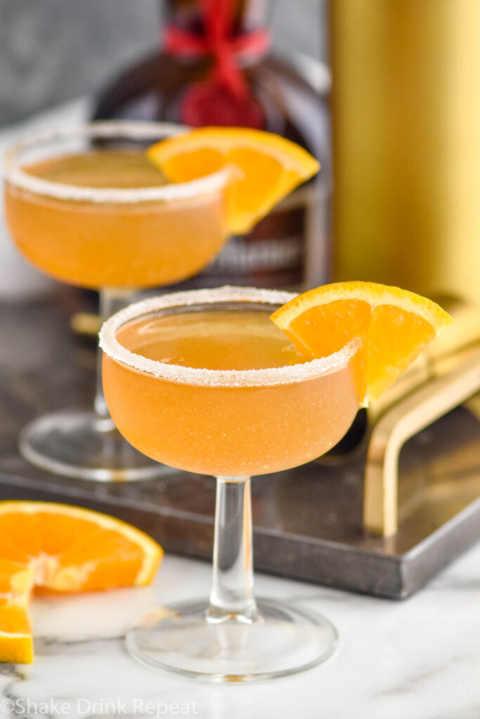 two glasses of Sidecar cocktails with sugared rim and orange slice garnish