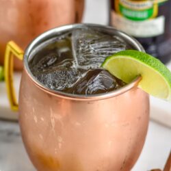 copper mug of Tequila Mule with ice, lime slice, and bottle of ginger beer