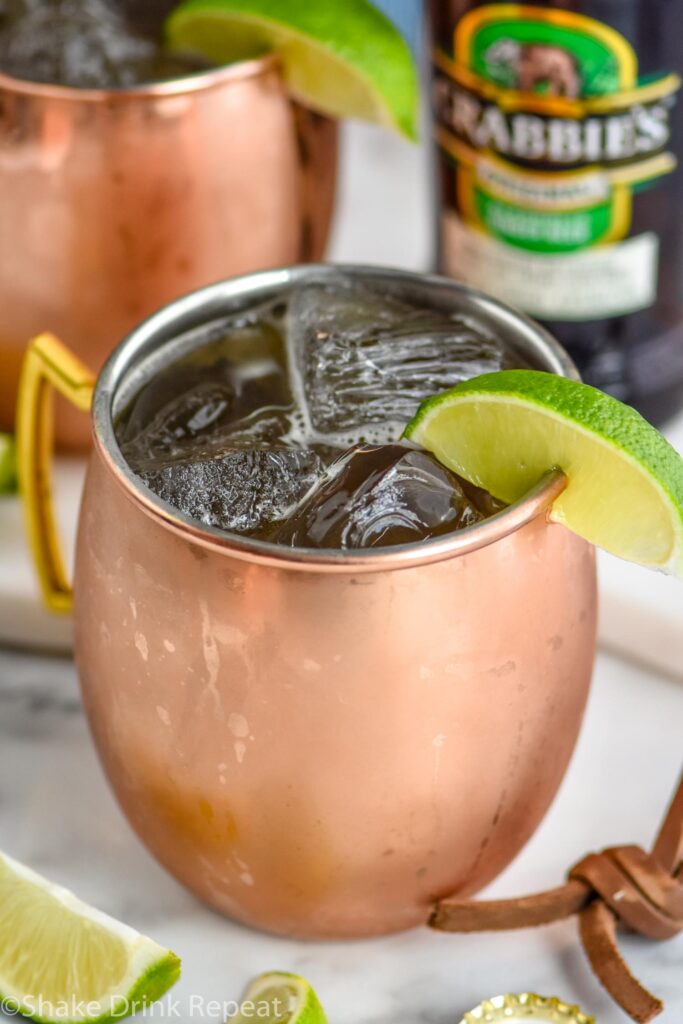 copper mug of Tequila Mule with ice, lime slice, and bottle of ginger beer