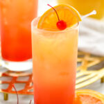 two glasses of tequila sunrise with ice and orange slice and cherry garnish