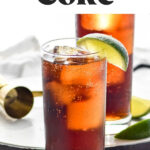 glass of rum and coke with ice and slices of lime