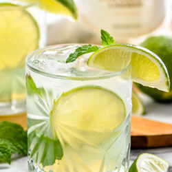 glass of Cojito with ice, slices of lime, and mint leaves with bottle of Malibu rum