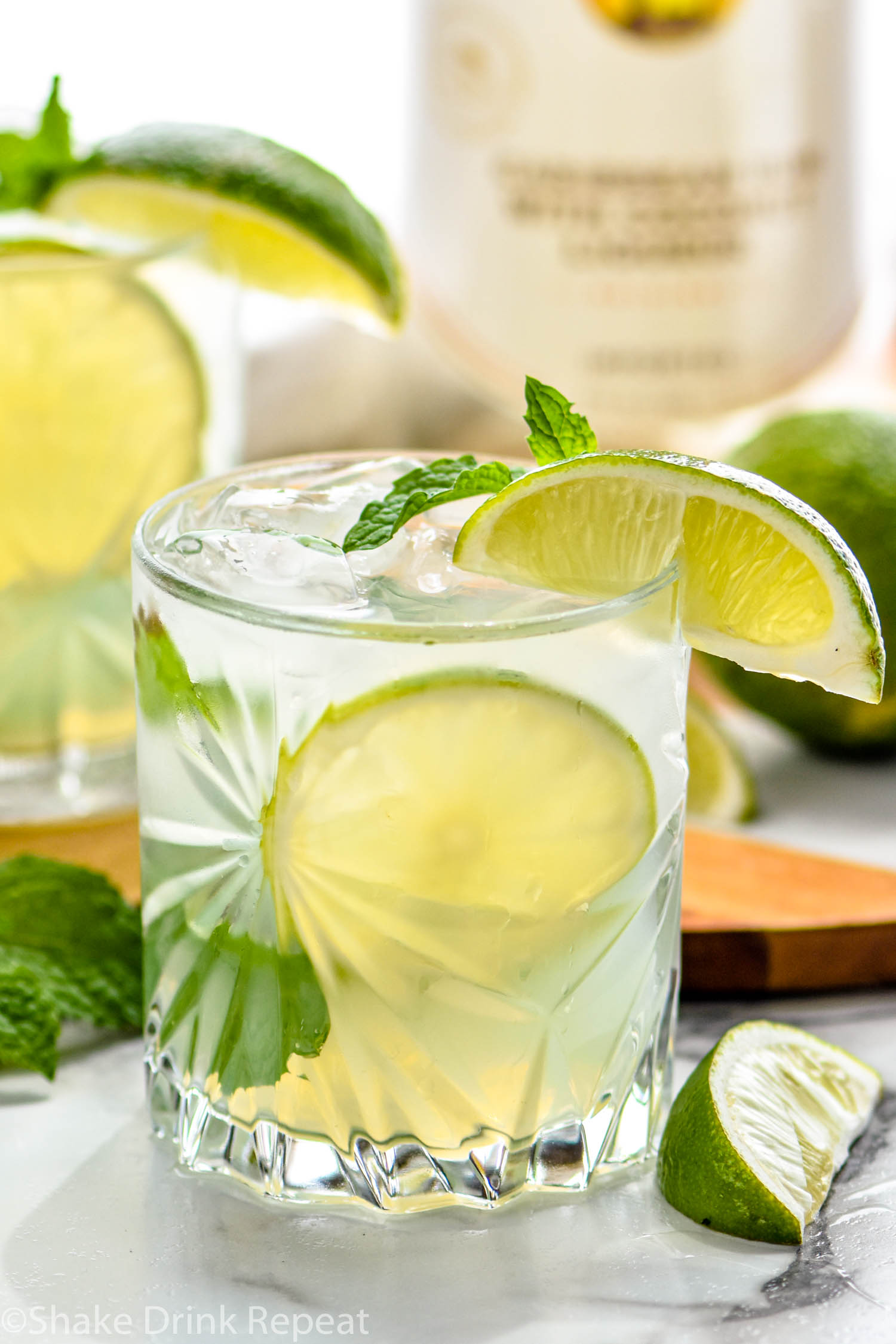 glass of Cojito with ice, slices of lime, and mint leaves with bottle of Malibu rum